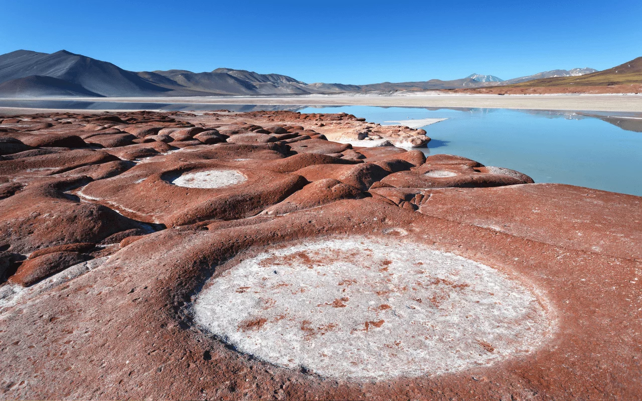 Formações rochosas vermelhas e lagoa no deserto do Atacama, no Chile